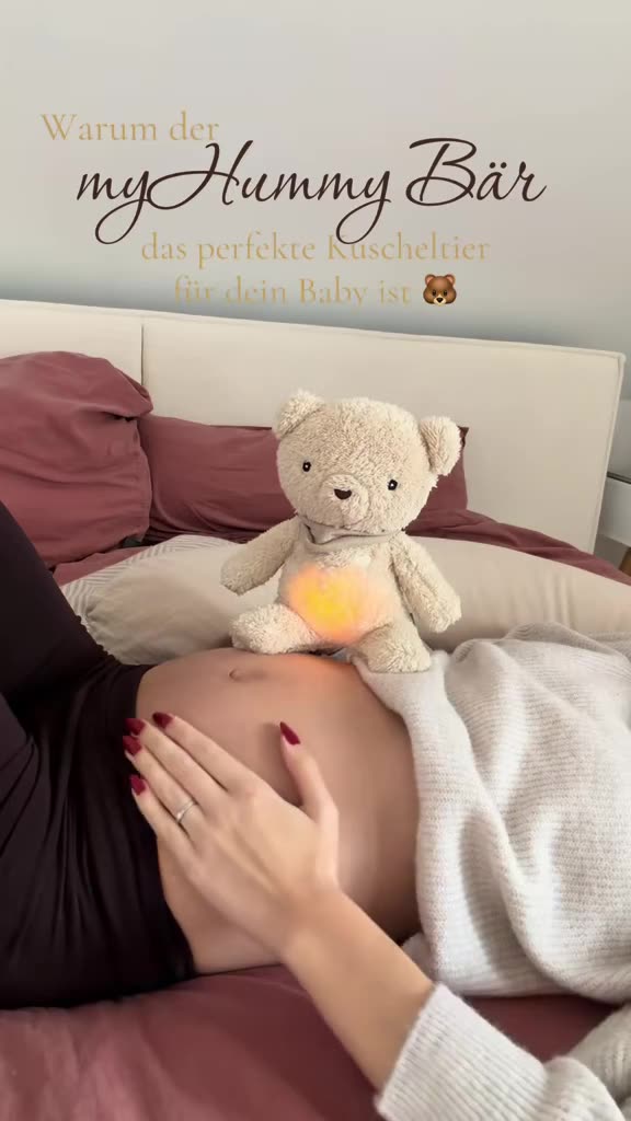 Ein Kuscheltier-Bär liegt neben einem Babybauch