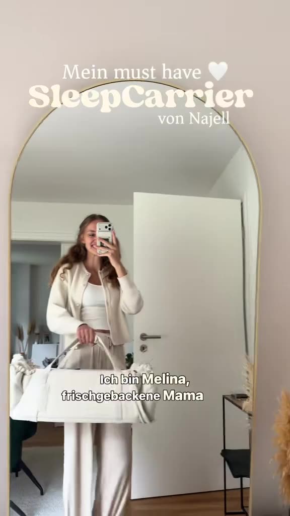 Melina fotografiert sich im Spiegel mit einer Babytragetasche